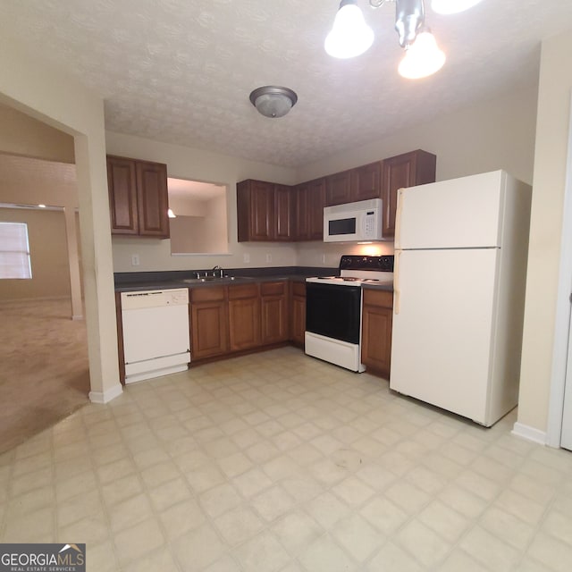 kitchen featuring a textured ceiling, white appliances, and sink