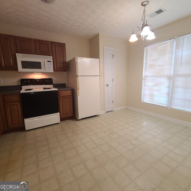 kitchen featuring a textured ceiling, hanging light fixtures, white appliances, and a notable chandelier