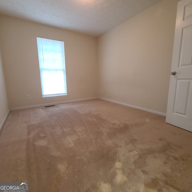 carpeted empty room featuring a textured ceiling