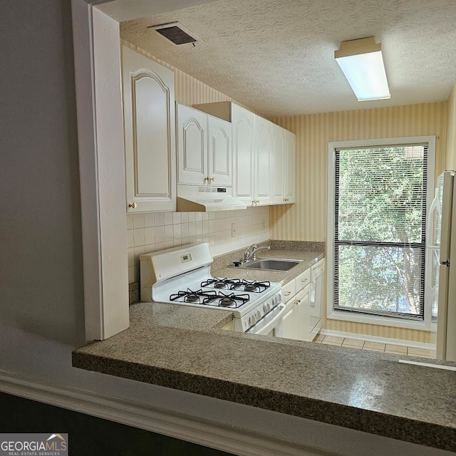 kitchen featuring sink, white appliances, a textured ceiling, backsplash, and white cabinetry