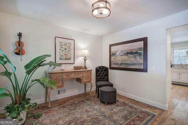 sitting room with wood finished floors, visible vents, and baseboards