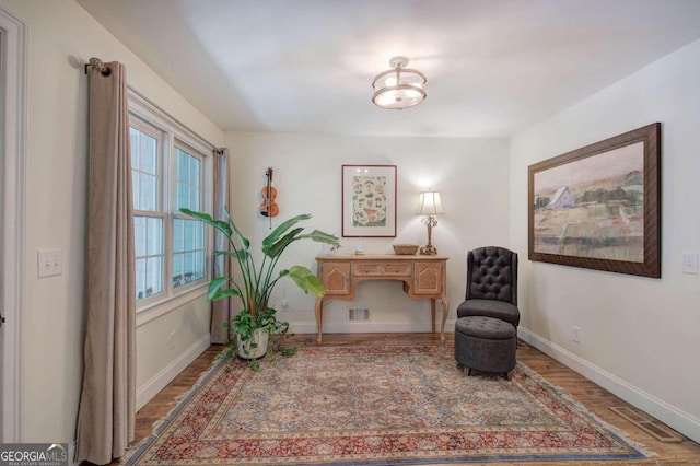 living area with wood finished floors, visible vents, and baseboards