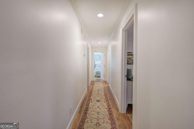 hall featuring light wood-type flooring, crown molding, baseboards, and recessed lighting