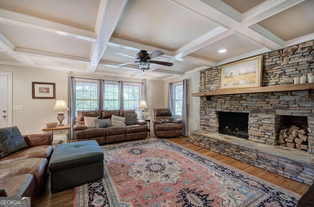 living room featuring a stone fireplace, wood finished floors, beam ceiling, and a ceiling fan