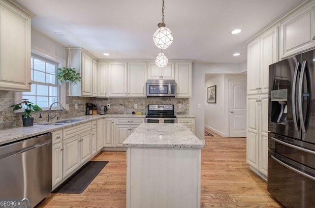 kitchen with a center island, decorative light fixtures, stainless steel appliances, white cabinets, and a sink