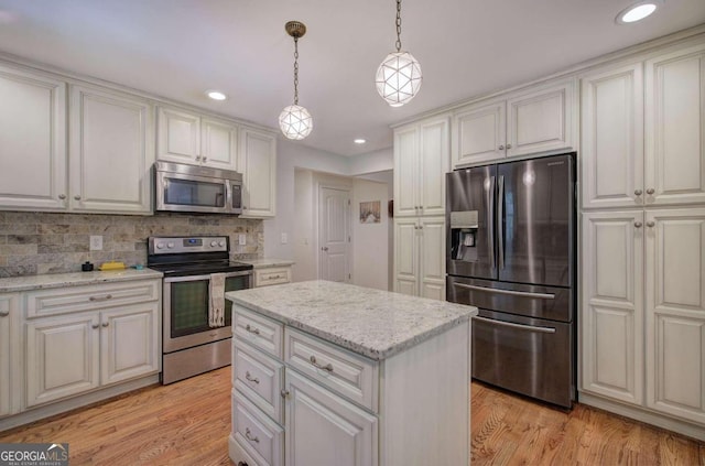 kitchen featuring light wood-style flooring, stainless steel appliances, a kitchen island, white cabinetry, and pendant lighting