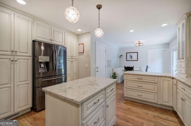 kitchen featuring light wood finished floors, a kitchen island, decorative light fixtures, and stainless steel fridge with ice dispenser