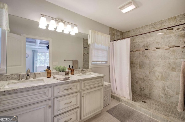 full bath with a sink, a tile shower, and double vanity