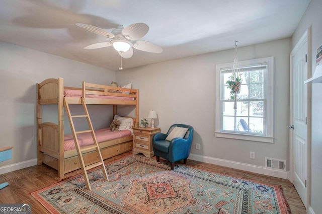 bedroom with a ceiling fan, baseboards, visible vents, and wood finished floors