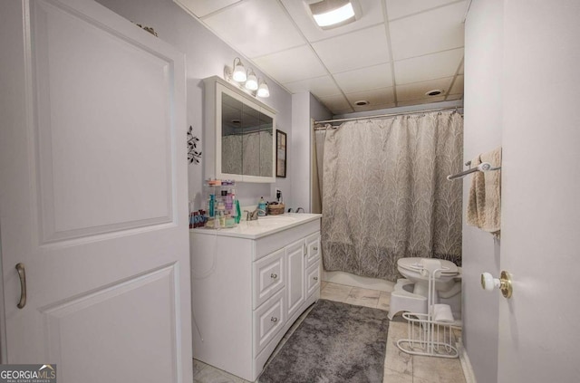 full bathroom featuring toilet, a drop ceiling, and vanity