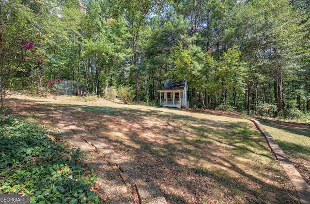 view of yard featuring an outdoor structure and a view of trees