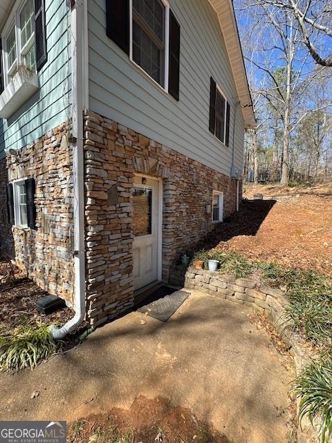 view of property exterior featuring stone siding and a patio area