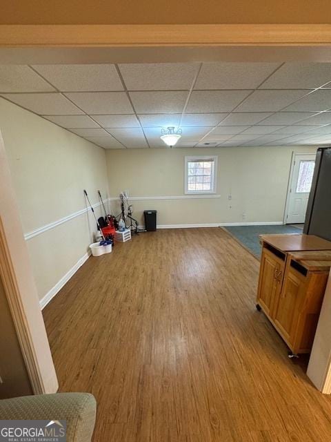 below grade area with a drop ceiling, baseboards, and wood finished floors