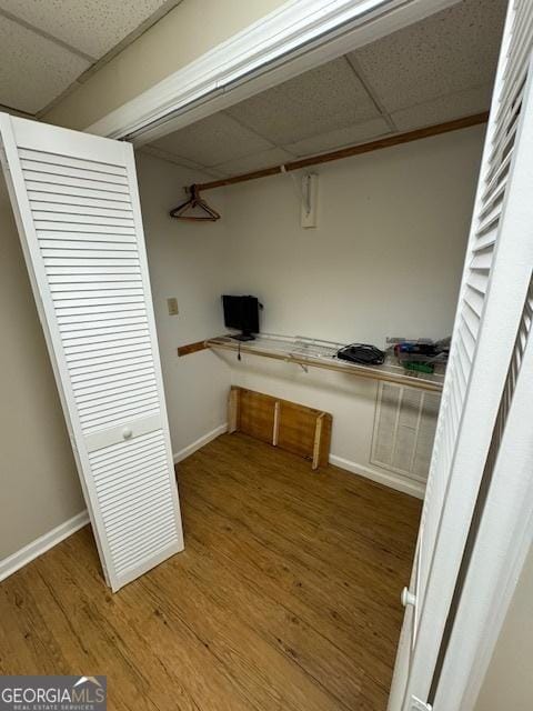 interior space featuring a paneled ceiling, baseboards, and wood finished floors