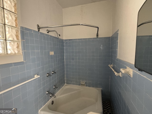 bathroom with tile walls and tiled shower / bath combo