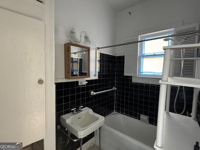 bathroom featuring sink, tiled shower / bath combo, and tile walls