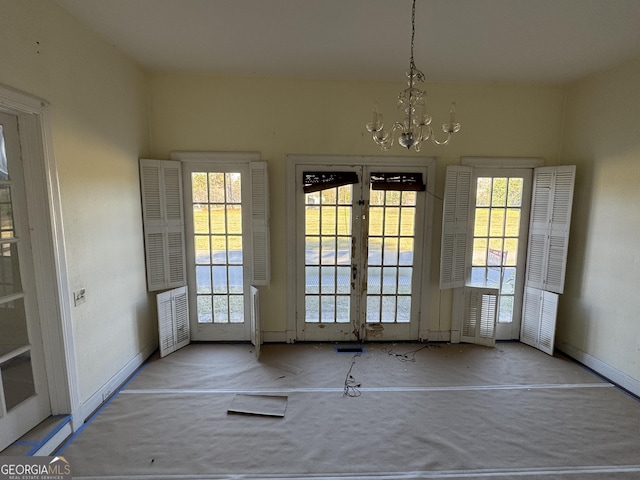 unfurnished dining area featuring plenty of natural light, french doors, and a notable chandelier