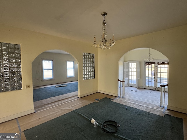 interior space featuring french doors, a wealth of natural light, and an inviting chandelier