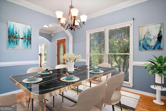 dining area featuring hardwood / wood-style flooring, crown molding, and a chandelier