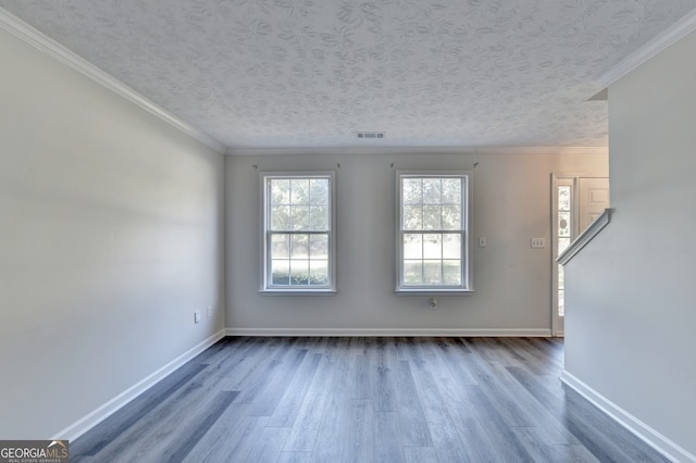 empty room with hardwood / wood-style flooring, a textured ceiling, and ornamental molding