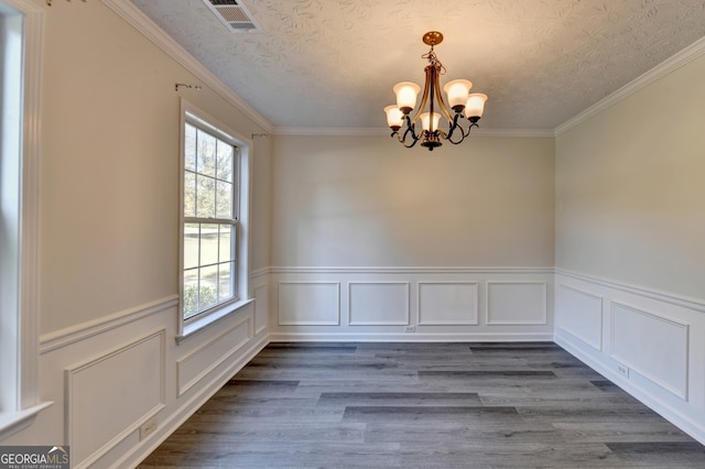 unfurnished dining area featuring dark hardwood / wood-style flooring, a notable chandelier, ornamental molding, and a wealth of natural light