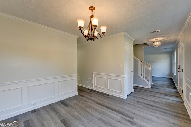 spare room featuring crown molding, a textured ceiling, a chandelier, and hardwood / wood-style floors