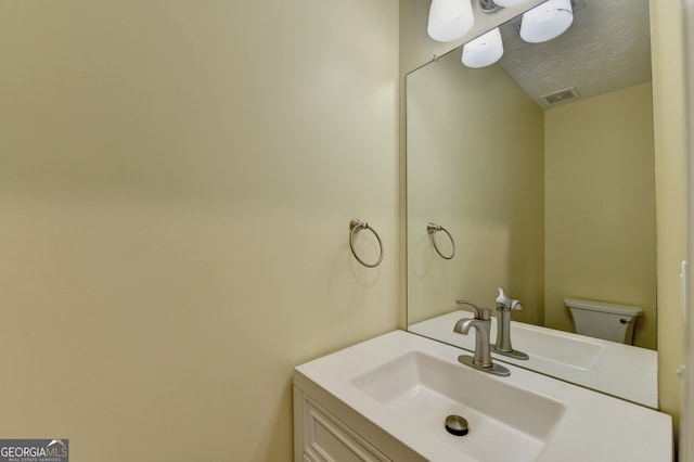 bathroom with vanity, a textured ceiling, and toilet