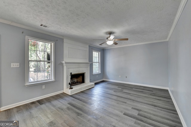 unfurnished living room with a textured ceiling, a fireplace, hardwood / wood-style flooring, and plenty of natural light