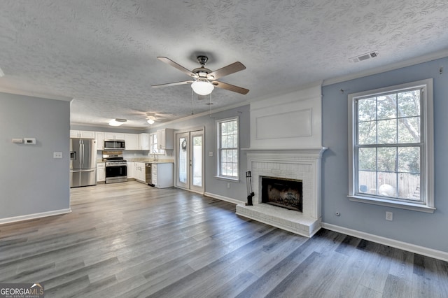 unfurnished living room with a textured ceiling, light wood-type flooring, and plenty of natural light