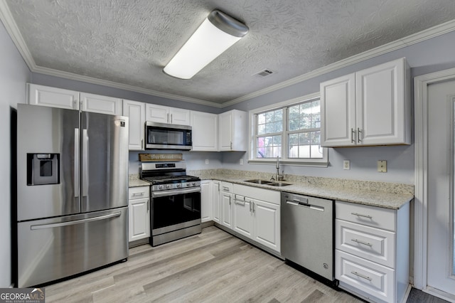 kitchen featuring stainless steel appliances, ornamental molding, sink, white cabinetry, and light hardwood / wood-style floors