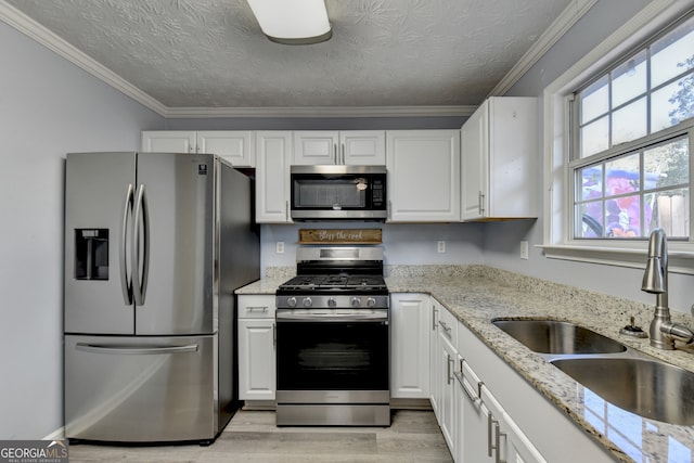 kitchen featuring stainless steel appliances, sink, light wood-type flooring, and white cabinets