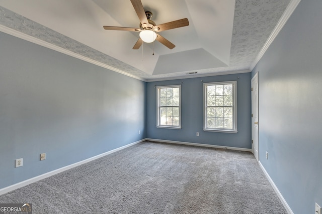 carpeted empty room featuring crown molding, ceiling fan, and a raised ceiling