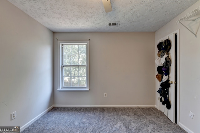 unfurnished room featuring carpet and a textured ceiling