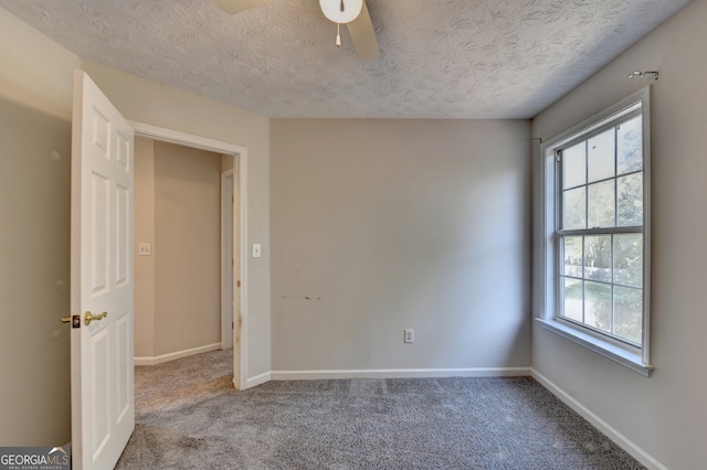 spare room featuring a textured ceiling, carpet floors, and ceiling fan