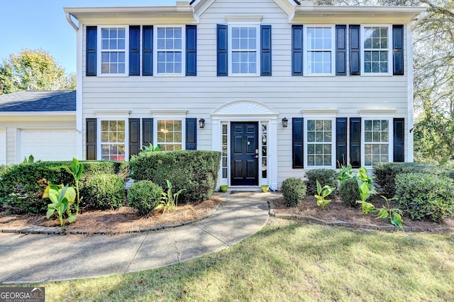 colonial house featuring a front yard and a garage