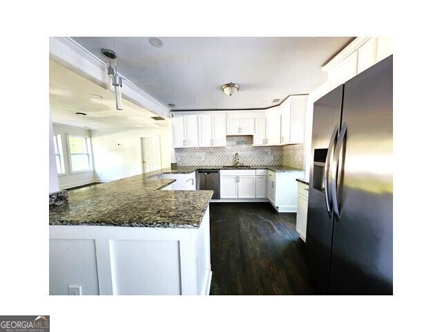 kitchen featuring hanging light fixtures, dark stone countertops, tasteful backsplash, stainless steel refrigerator with ice dispenser, and sink