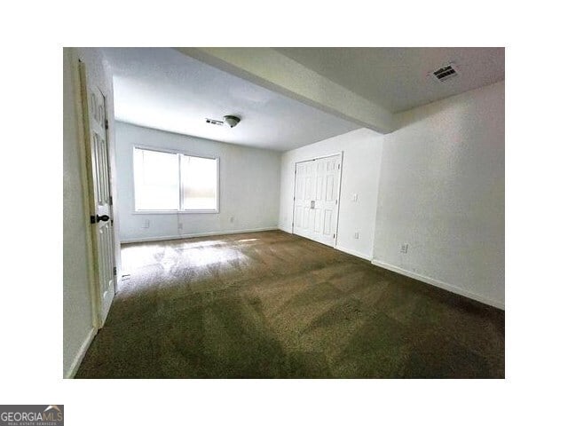 carpeted empty room with beam ceiling