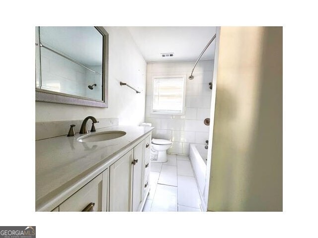 full bathroom with tiled shower / bath combo, vanity, tile patterned flooring, and toilet