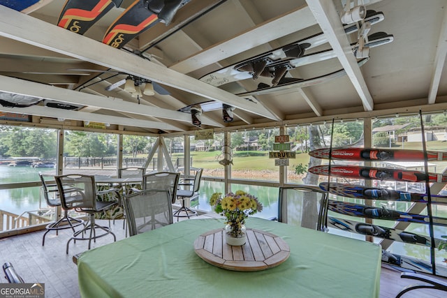 sunroom featuring a water view and vaulted ceiling