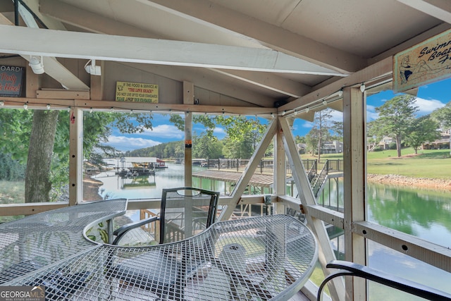 sunroom featuring a water view and vaulted ceiling with beams