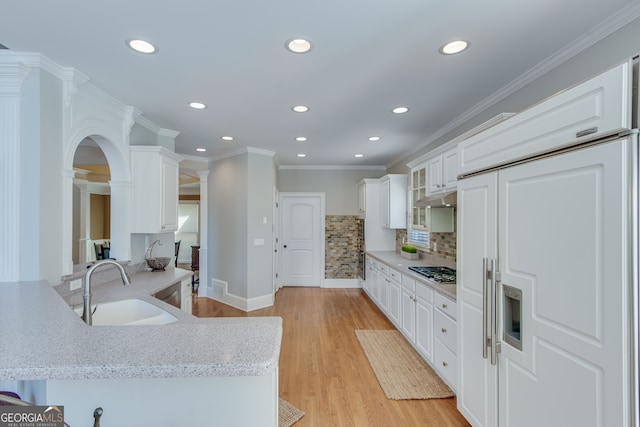 kitchen with stainless steel gas cooktop, sink, crown molding, white cabinets, and light wood-type flooring