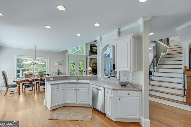 kitchen with light hardwood / wood-style floors, white cabinetry, sink, stainless steel dishwasher, and pendant lighting