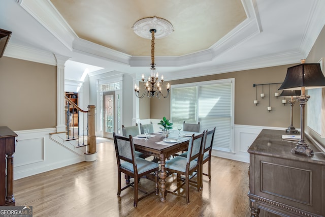 dining area featuring light wood-type flooring, a tray ceiling, crown molding, and plenty of natural light