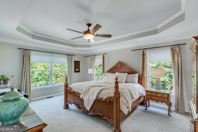 bedroom featuring light colored carpet, ceiling fan, ornamental molding, and a tray ceiling