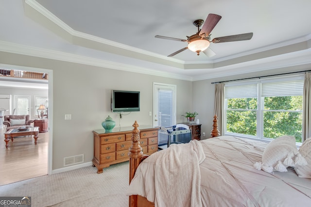 carpeted bedroom featuring ornamental molding, a tray ceiling, and ceiling fan