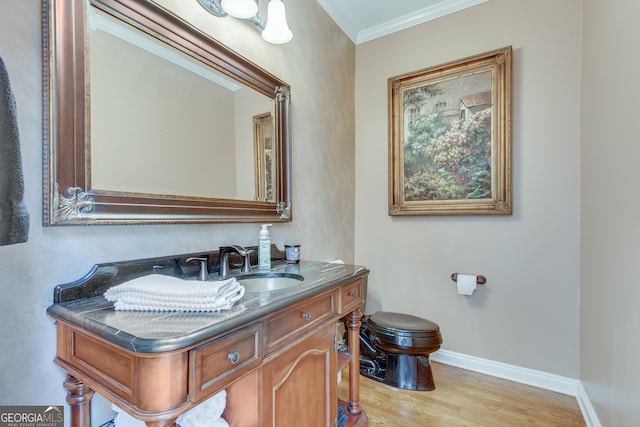 bathroom with toilet, hardwood / wood-style floors, vanity, and crown molding