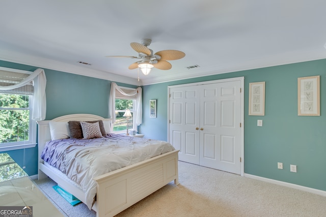 carpeted bedroom with ceiling fan, crown molding, and a closet