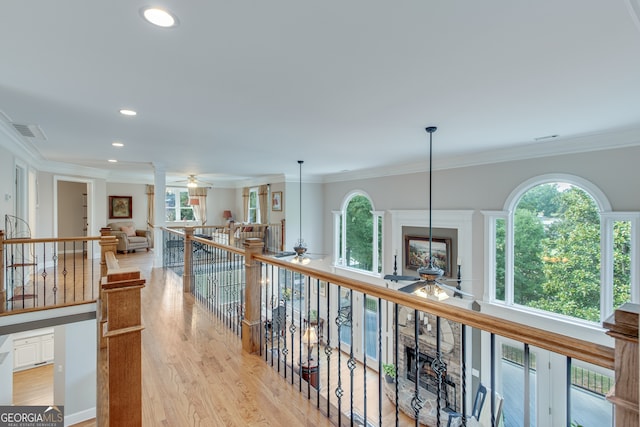 corridor with a wealth of natural light, light hardwood / wood-style flooring, and crown molding