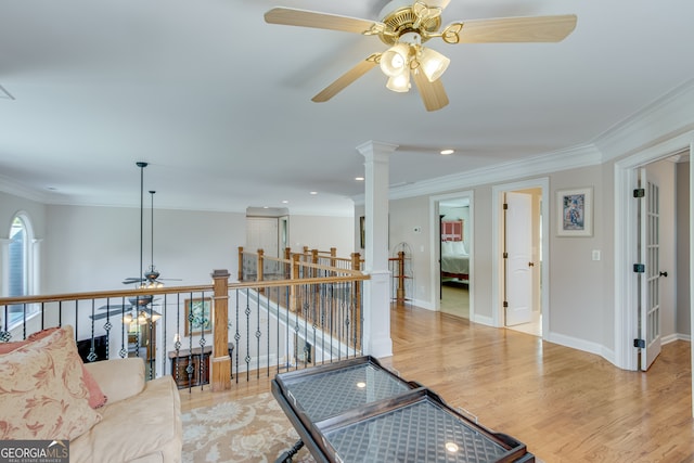 interior space featuring light hardwood / wood-style floors, ceiling fan, ornate columns, and ornamental molding