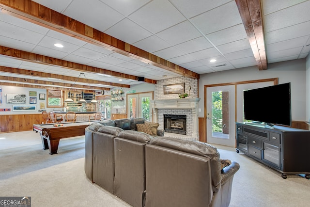 living room featuring french doors, plenty of natural light, wood walls, and light carpet